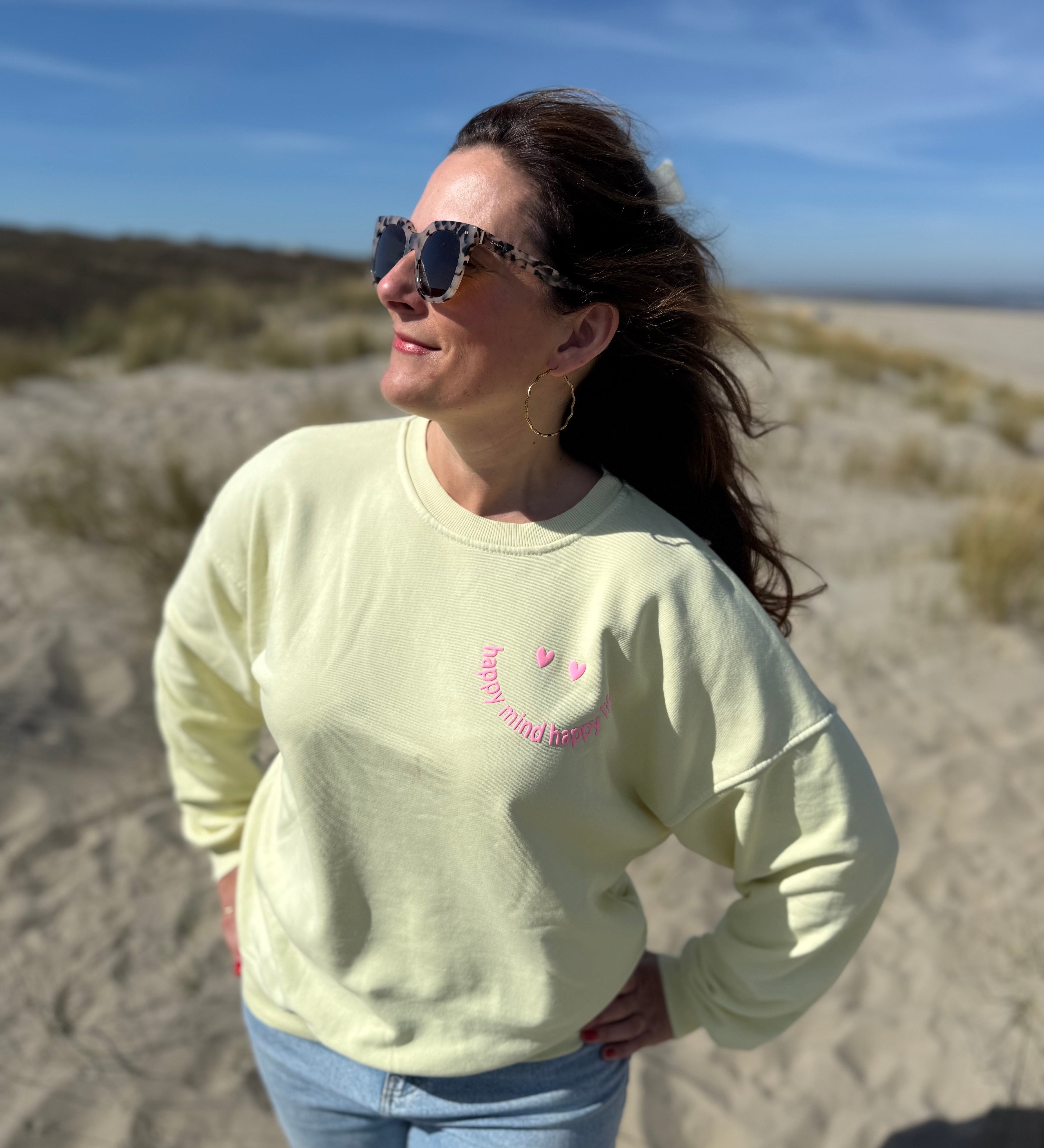 Locker geschnittenes Sweatshirt in rosa mit einem orangenen Smiley auf der Brust.