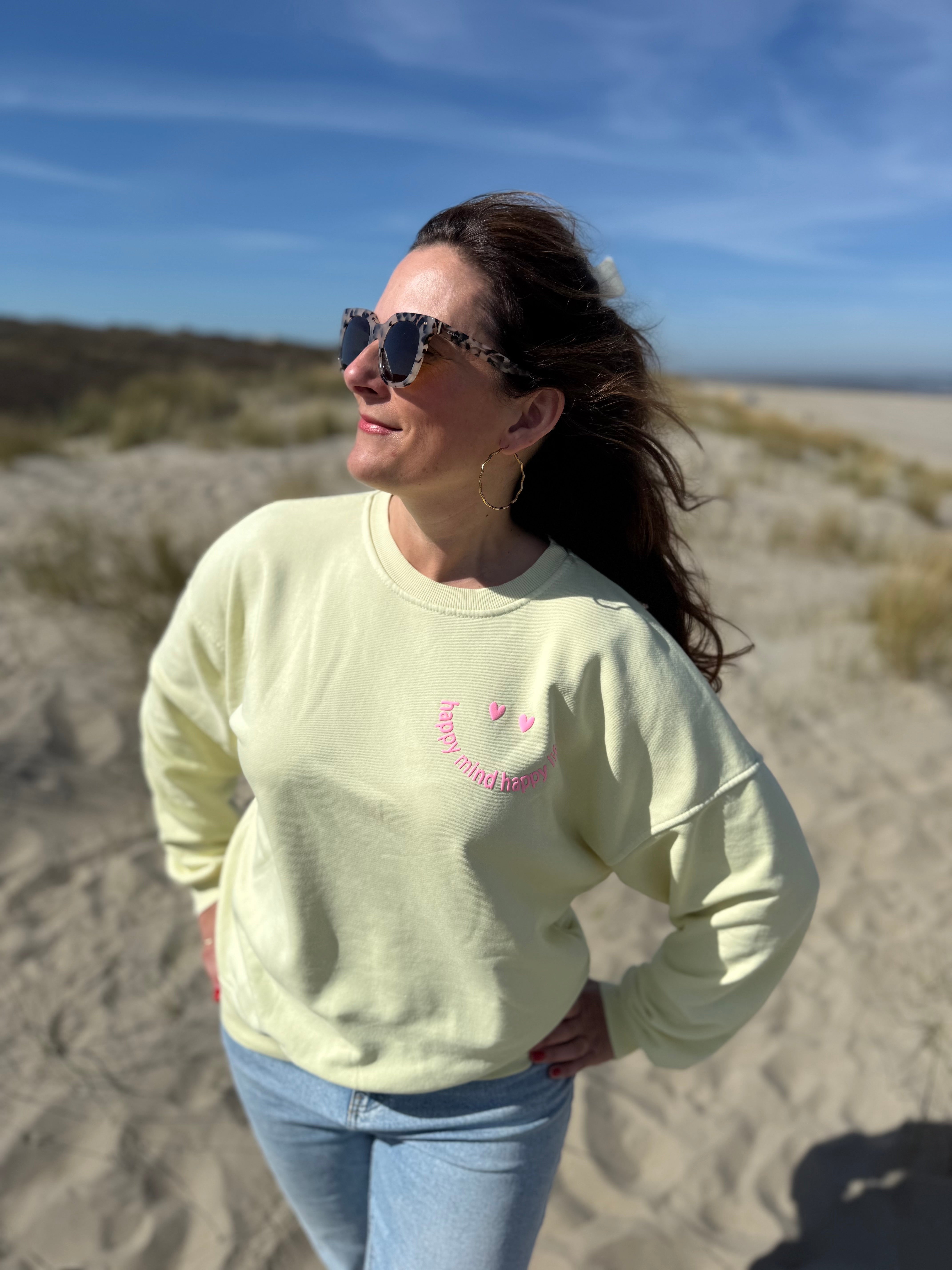 Locker geschnittenes Sweatshirt in rosa mit einem orangenen Smiley auf der Brust.