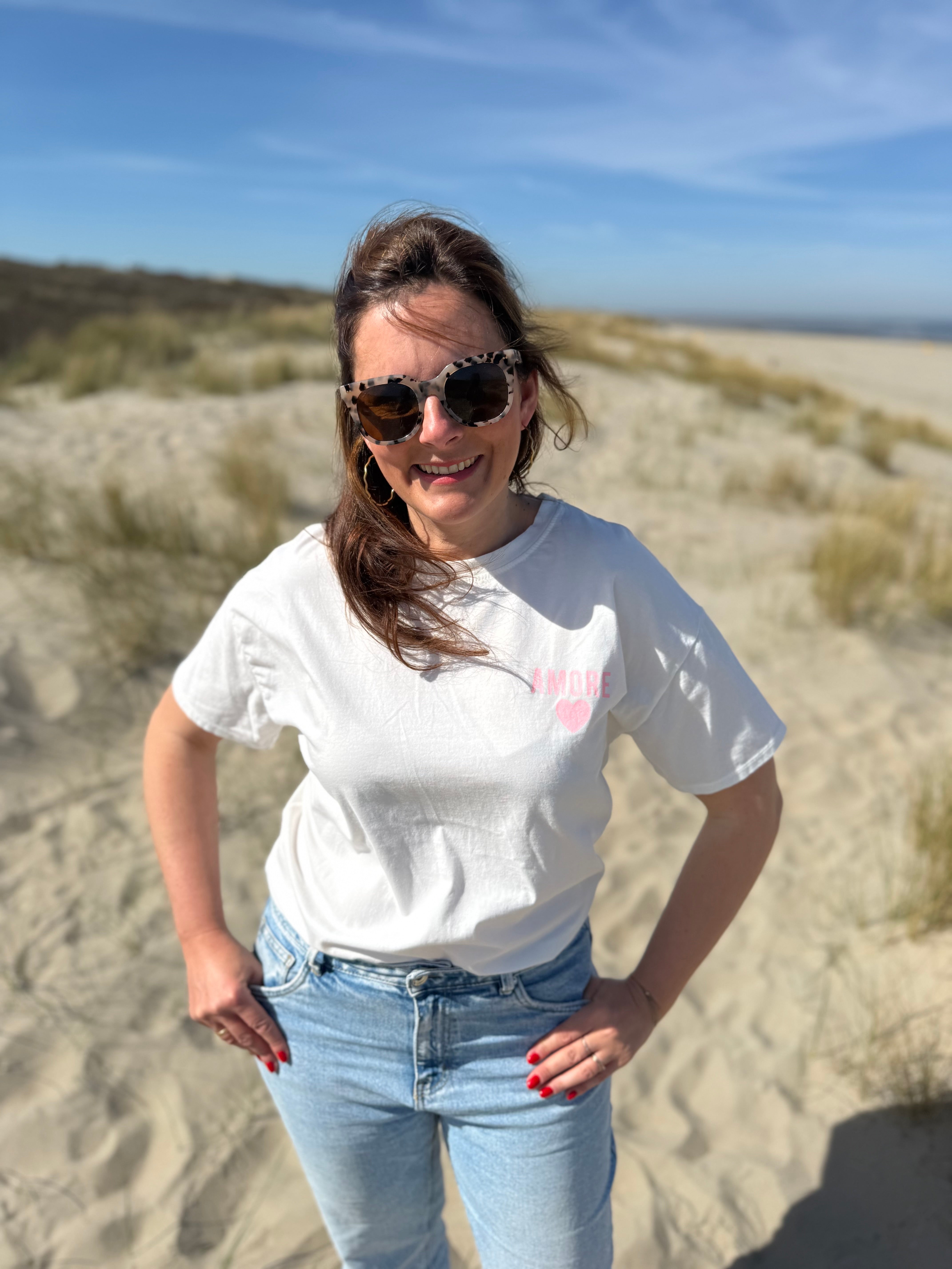 Oversize T-Shirt zum Verlieben. Kleines süßes Herz auf der Brust und ein großer Statement Print auf dem Rücken in rosa mit Amore. Das T-Shirt ist weiß.
