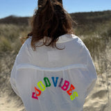 Musselinbluse im lockeren Oversize Look mit langen Ärmeln. Eyecatcher ist ein bunter GOOD VIBES Aufdruck am Rücken. Die Bluse ist weiß.