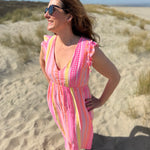Musselinkleid in Maxilänge mit V Ausschnitt und kurzen Flügelärmeln. Das Kleid ist rosa mit pink, gelb und orangenen Ethno Muster.