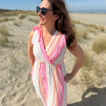 Musselinkleid in Midilänge mit V Ausschnitt. Es ist ärmellos und hat Schleifen an den Schultern zum binden. Das Kleid ist weiß mit pink und orangenen Ethno Muster.