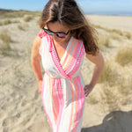 Musselinkleid in Midilänge mit V Ausschnitt. Es ist ärmellos und hat Schleifen an den Schultern zum binden. Das Kleid ist weiß mit pink und orangenen Ethno Muster.