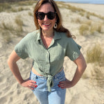Musselinbluse in cropped Schnitt zum binden. Die Bluse hat kurze Flügelärmel und ist salbei grün.