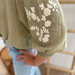 Leichte locker sitzende Baumwollbluse in salbei mit beigen Blumenstickereien an den Ärmeln.