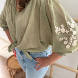 Leichte locker sitzende Baumwollbluse in salbei mit beigen Blumenstickereien an den Ärmeln.