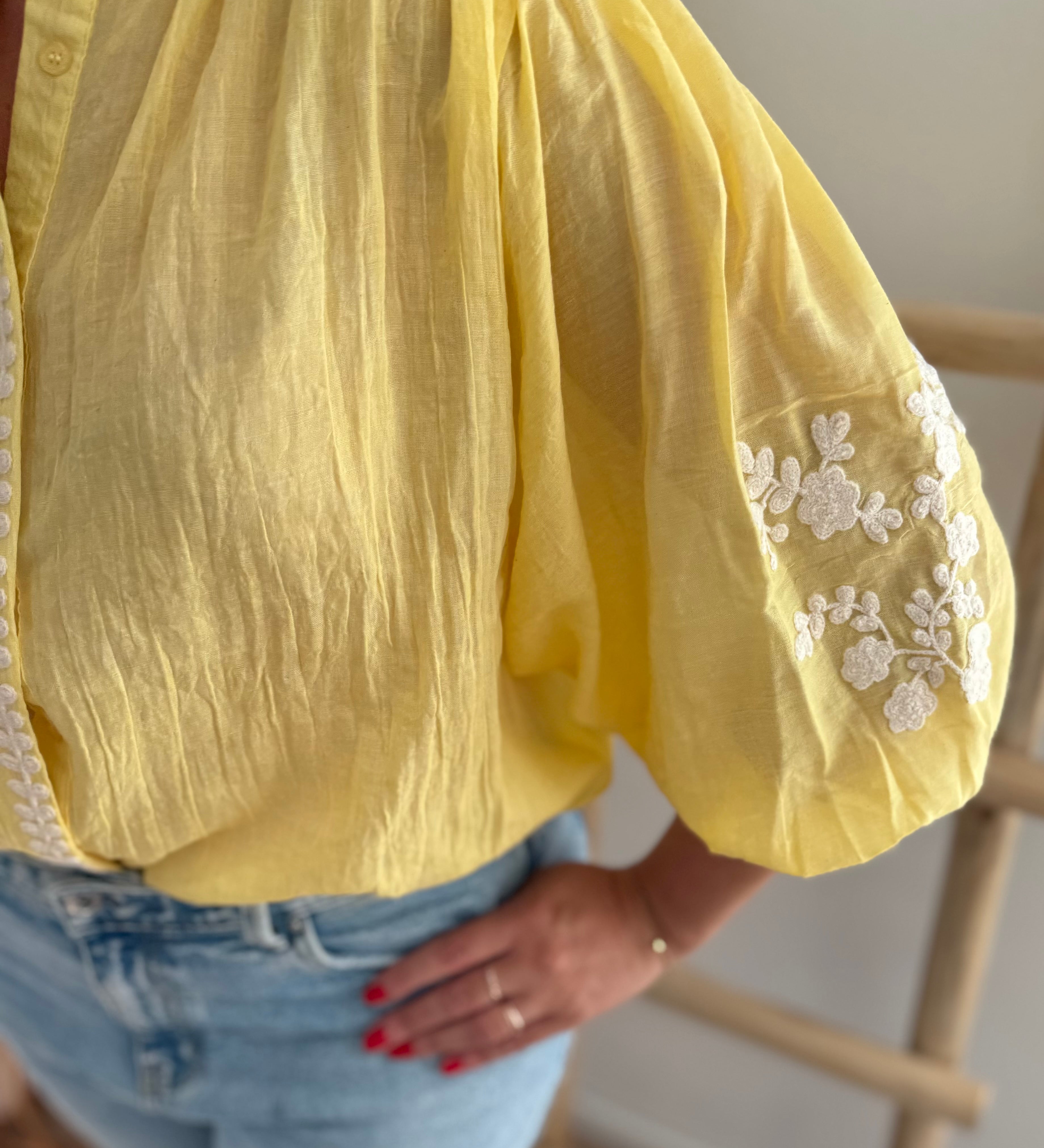 Leichte locker sitzende Baumwollbluse in gelb mit beigen Blumenstickereien an den Ärmeln.
