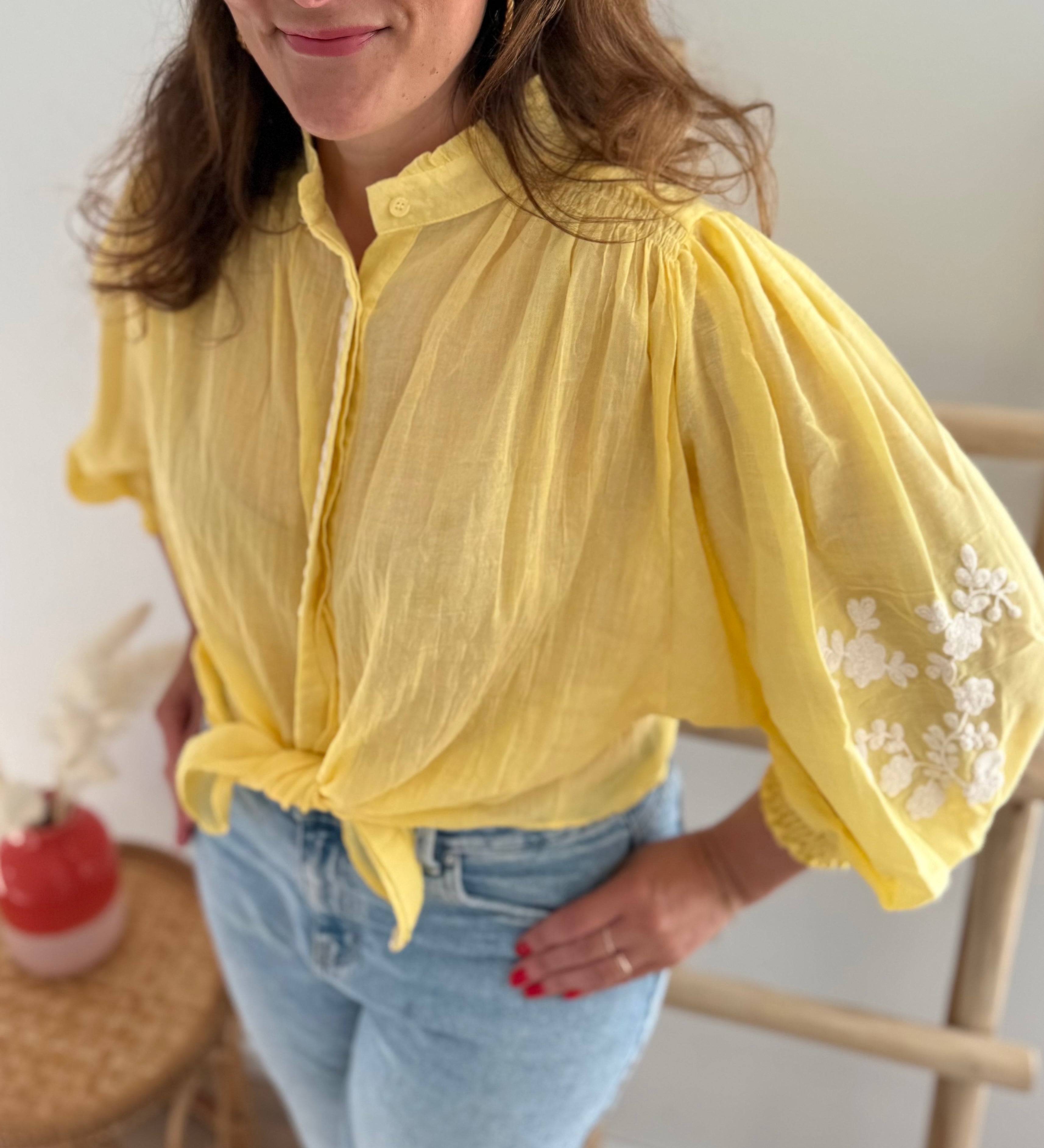 Leichte locker sitzende Baumwollbluse in gelb mit beigen Blumenstickereien an den Ärmeln.