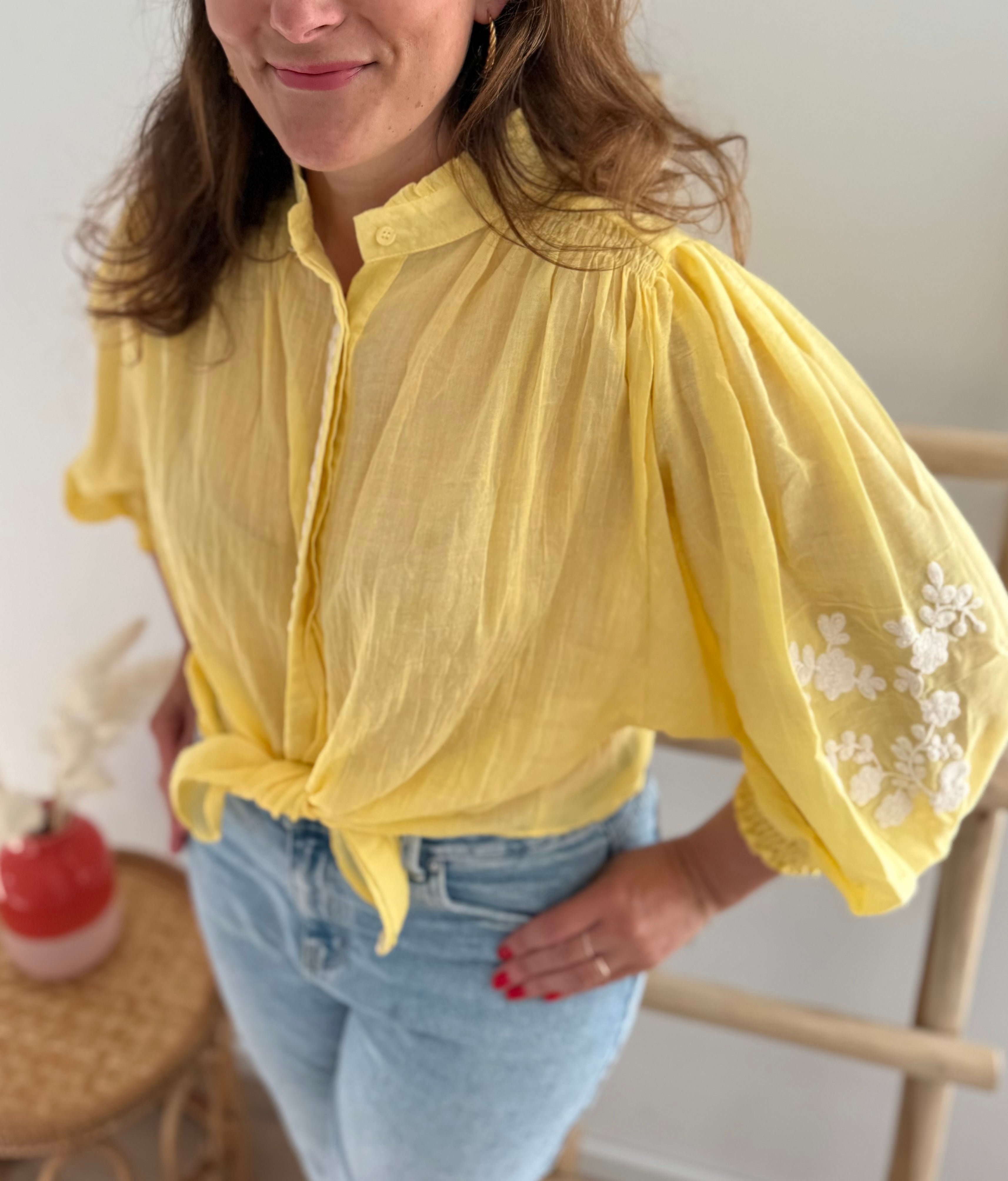 Leichte locker sitzende Baumwollbluse in gelb mit beigen Blumenstickereien an den Ärmeln.