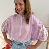 Leichte locker sitzende Baumwollbluse in flieder mit beigen Blumenstickereien an den Ärmeln.