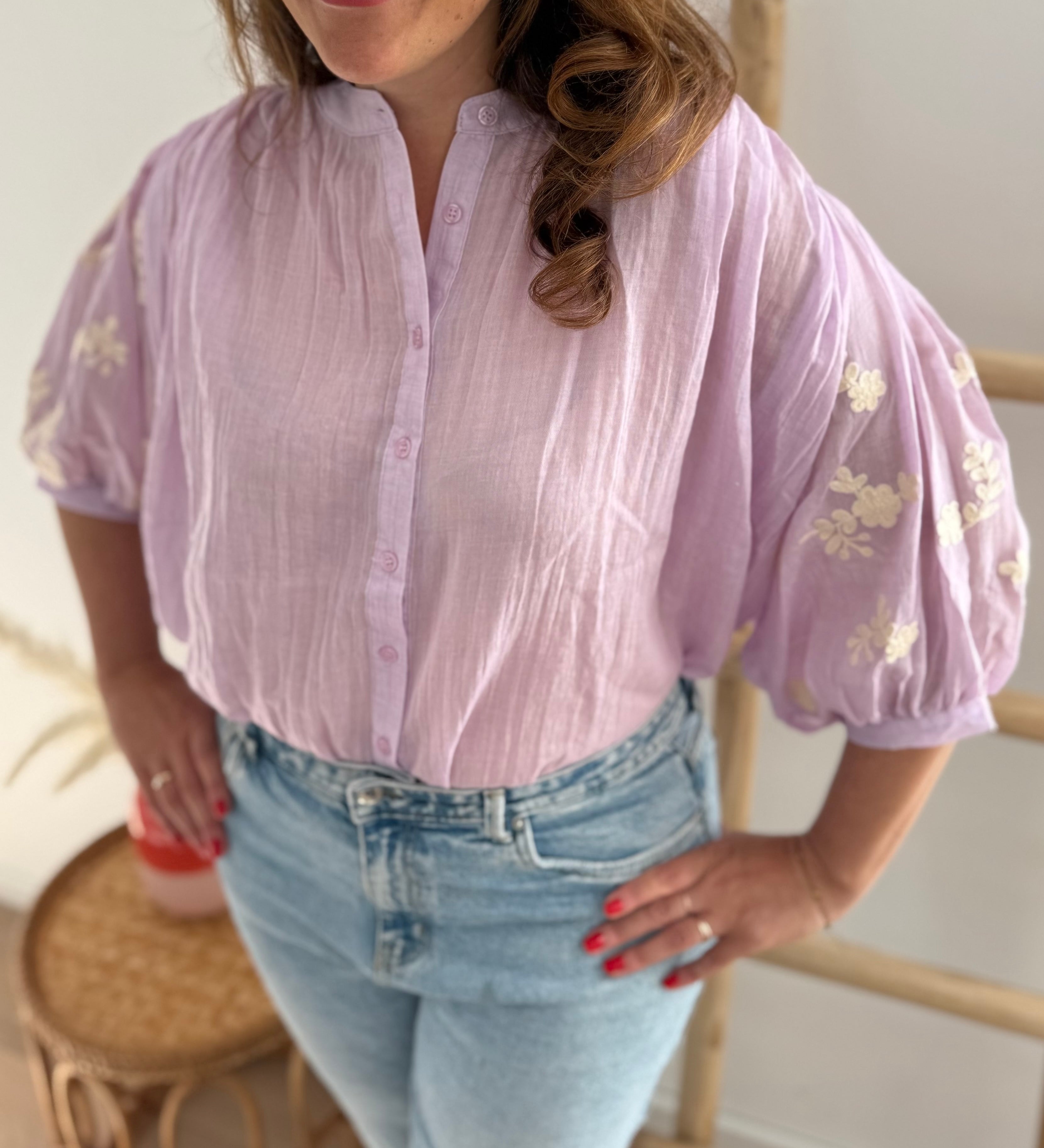 Leichte locker sitzende Baumwollbluse in flieder mit beigen Blumenstickereien an den Ärmeln.