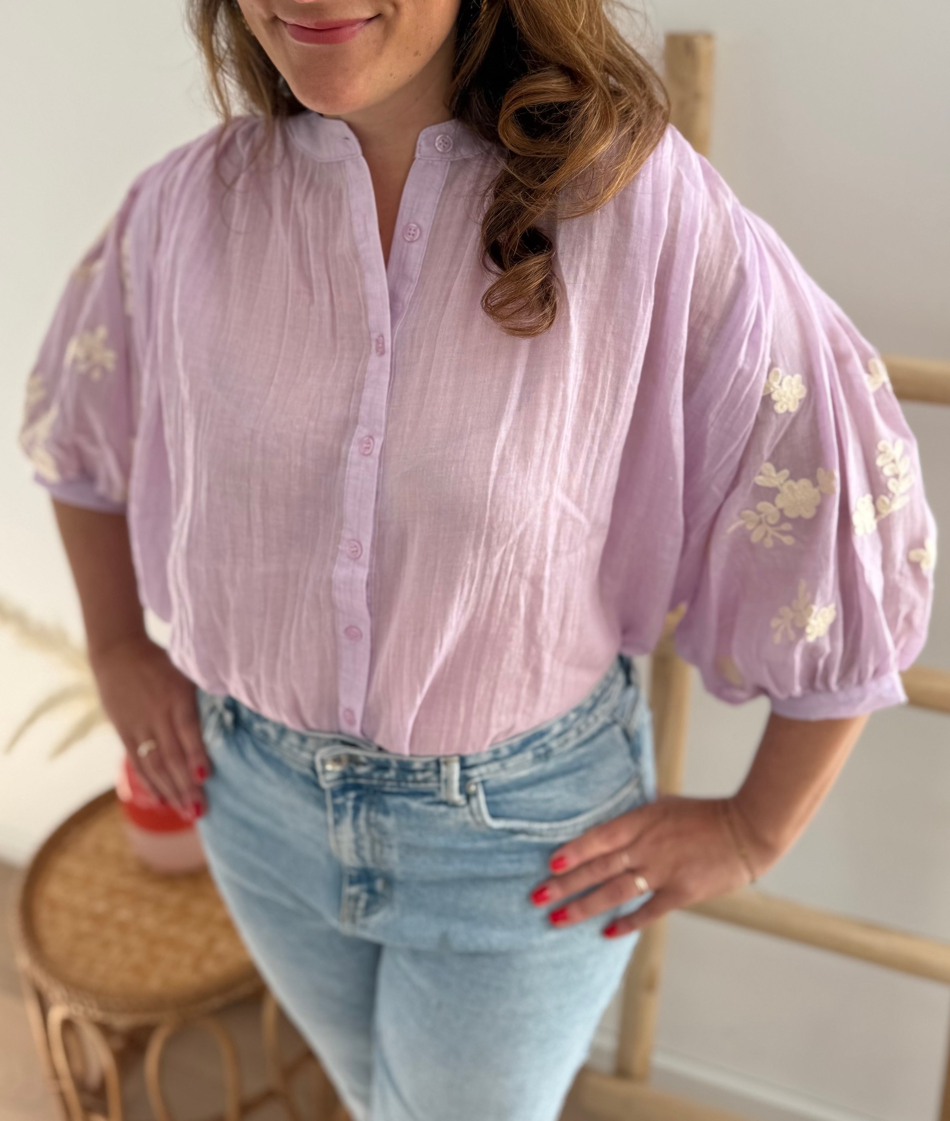 Leichte locker sitzende Baumwollbluse in flieder mit beigen Blumenstickereien an den Ärmeln.