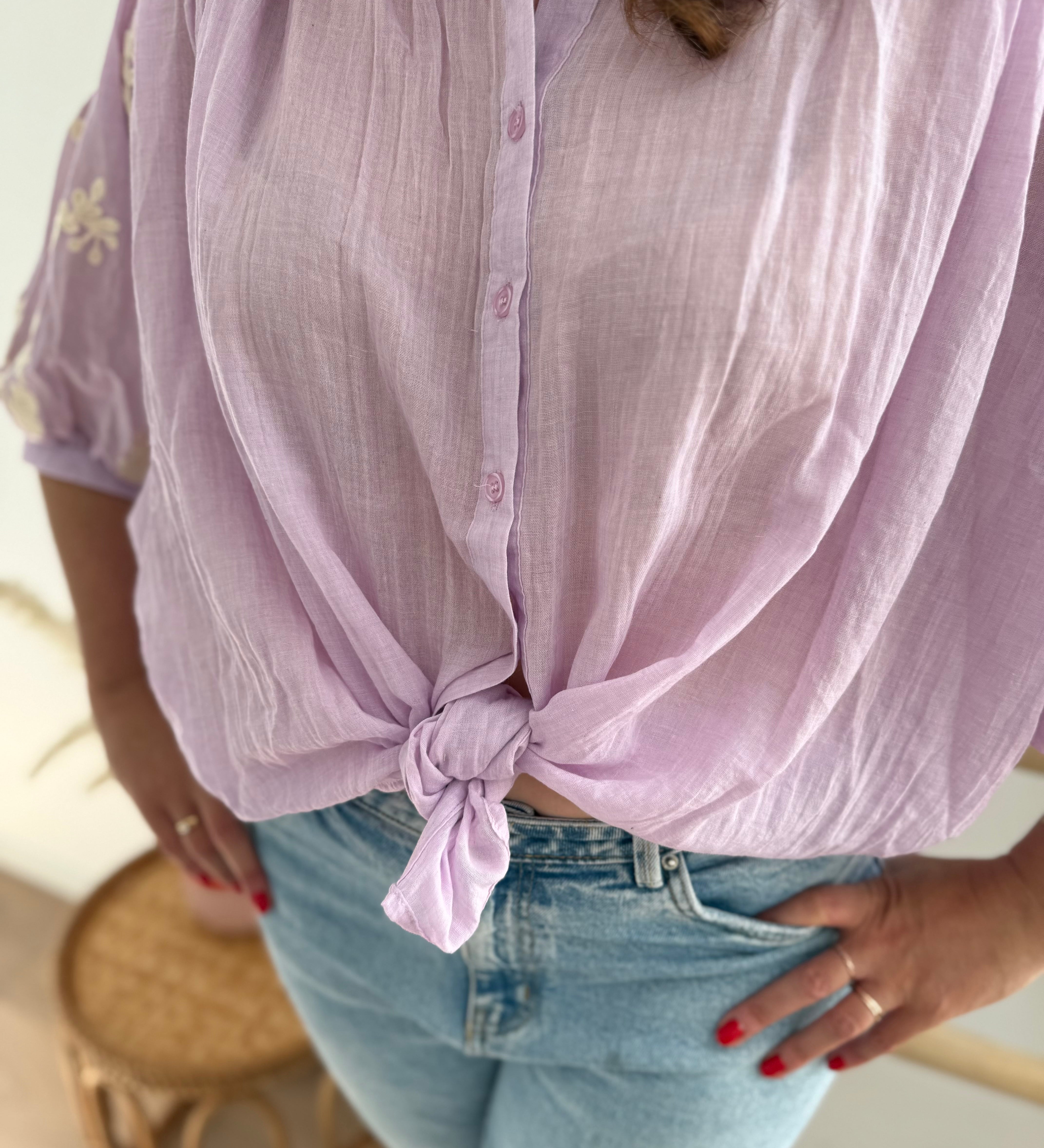 Leichte locker sitzende Baumwollbluse in flieder mit beigen Blumenstickereien an den Ärmeln.